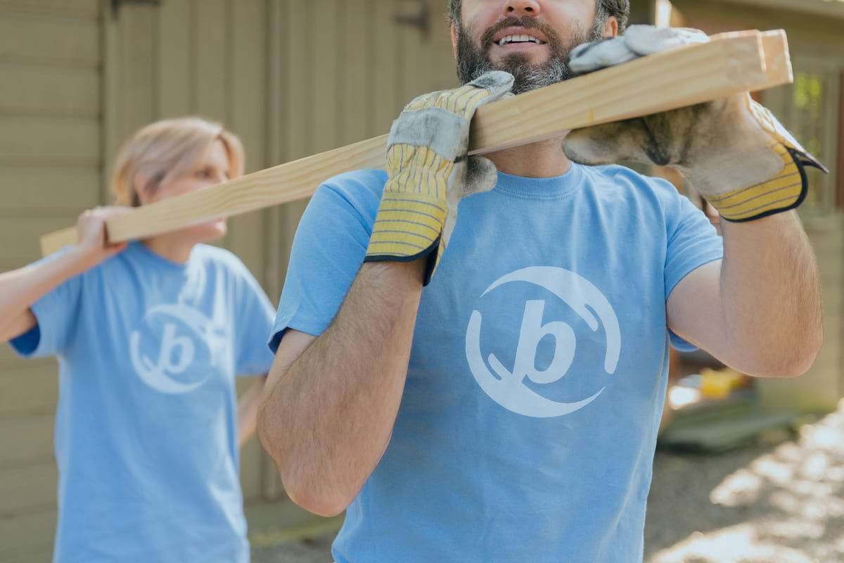 Two bizcom cares employees carrying a 2 by 4.